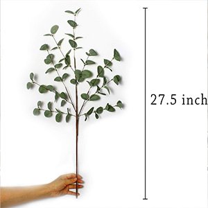 Hand holding a single 27.5-inch faux eucalyptus stem with green silk leaves against a white background.