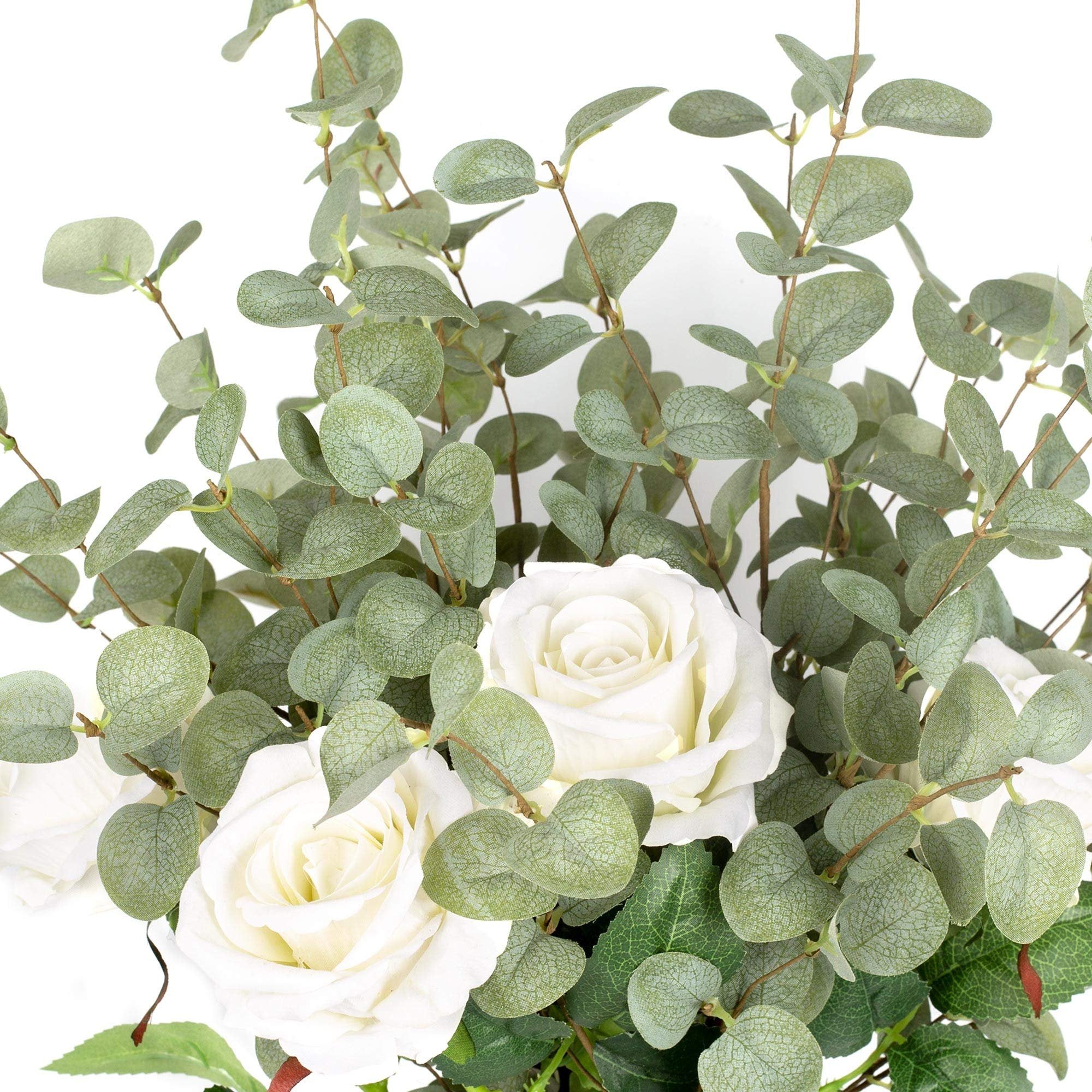 Close-up of faux eucalyptus stems with white roses against a white background.