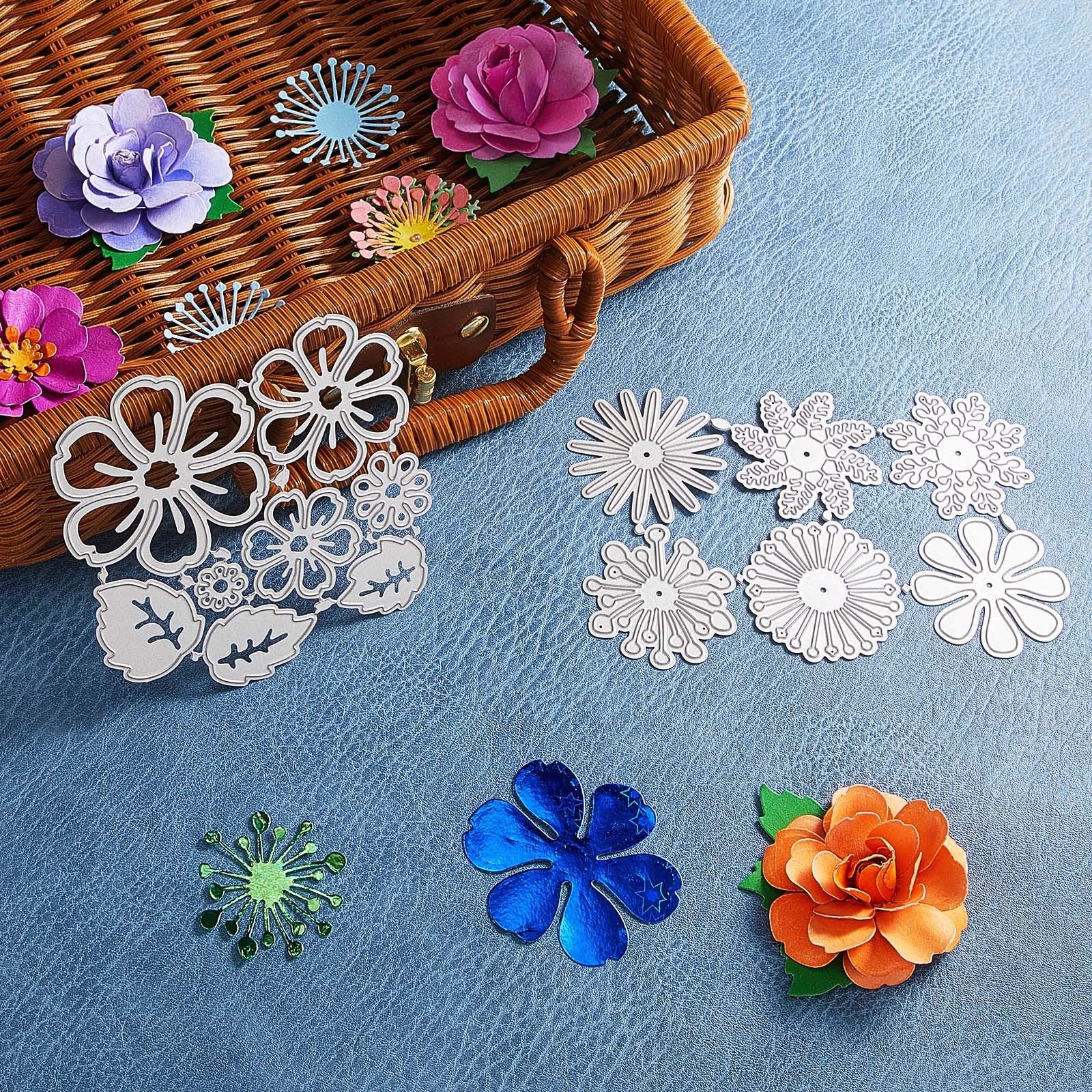 Flower and leaf metal cutting dies arranged with paper flowers and a woven basket.