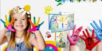 Smiling girl with colorful paint on her hands and drawings on the wall behind her