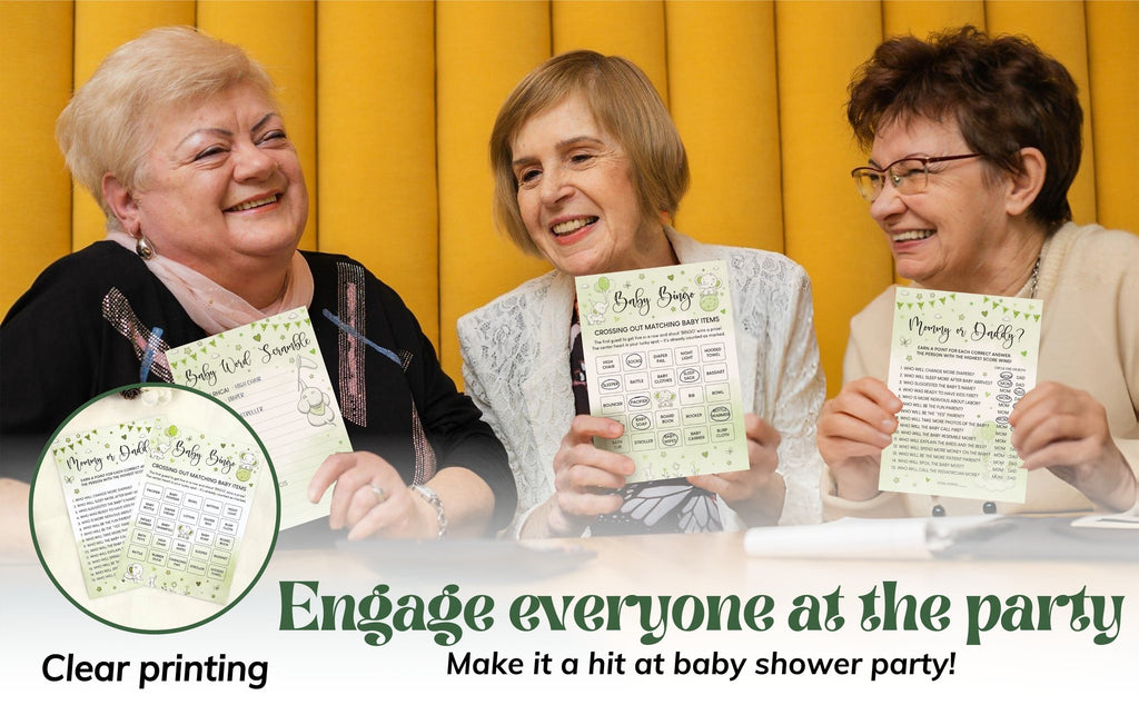 Three women smiling and holding baby shower game cards with a greenery theme.