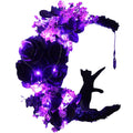 Halloween wreath with black cat silhouette reaching for a crystal, adorned with purple roses, flowers, greenery, and fairy lights on a white background.
