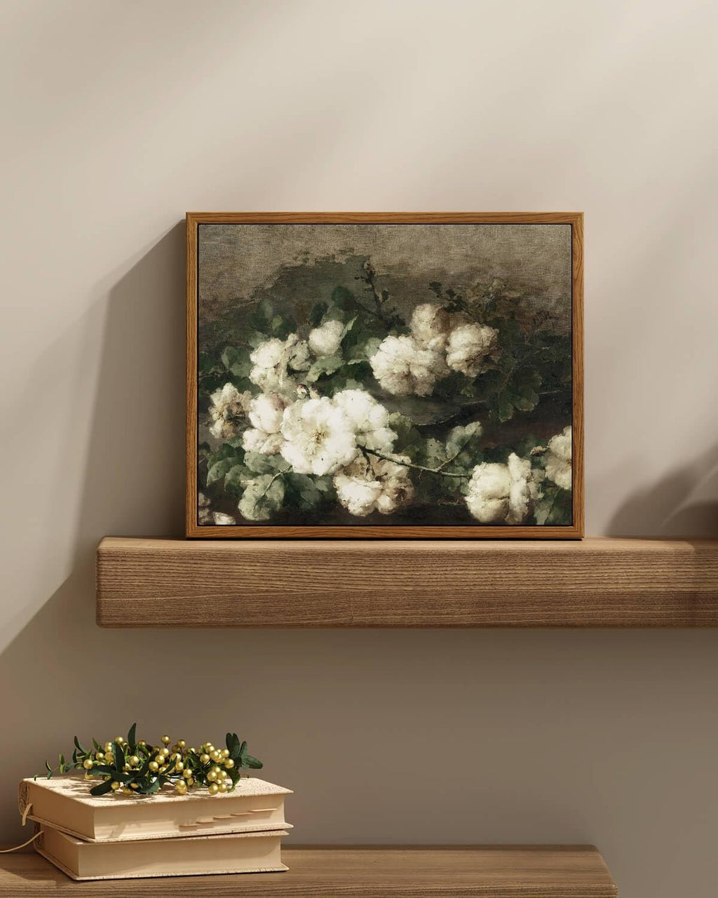 Framed vintage botanical flower print with white roses and green leaves displayed on a wooden shelf above stacked books.