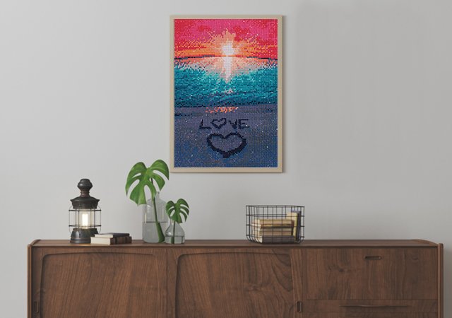 Framed diamond painting of a beach sunset with the word LOVE and a heart drawn in the sand