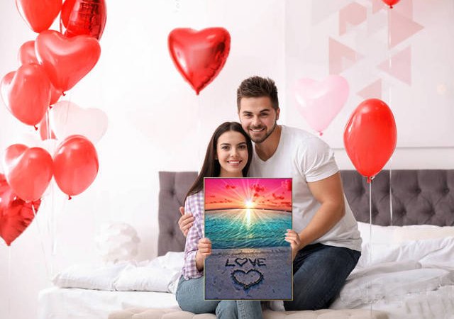 Couple holding a diamond painting kit of a beach sunset with 'LOVE' written in the sand