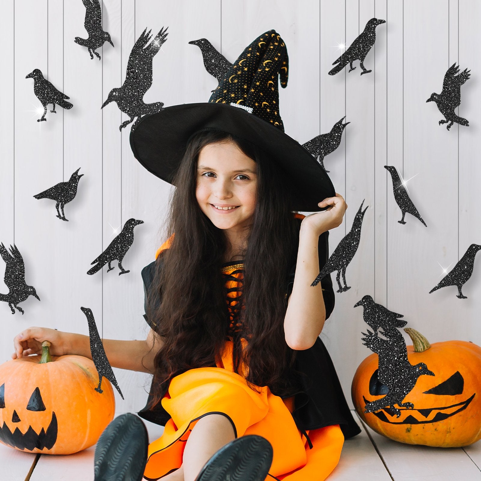 Young girl in witch costume with glitter black crows and pumpkins for Halloween