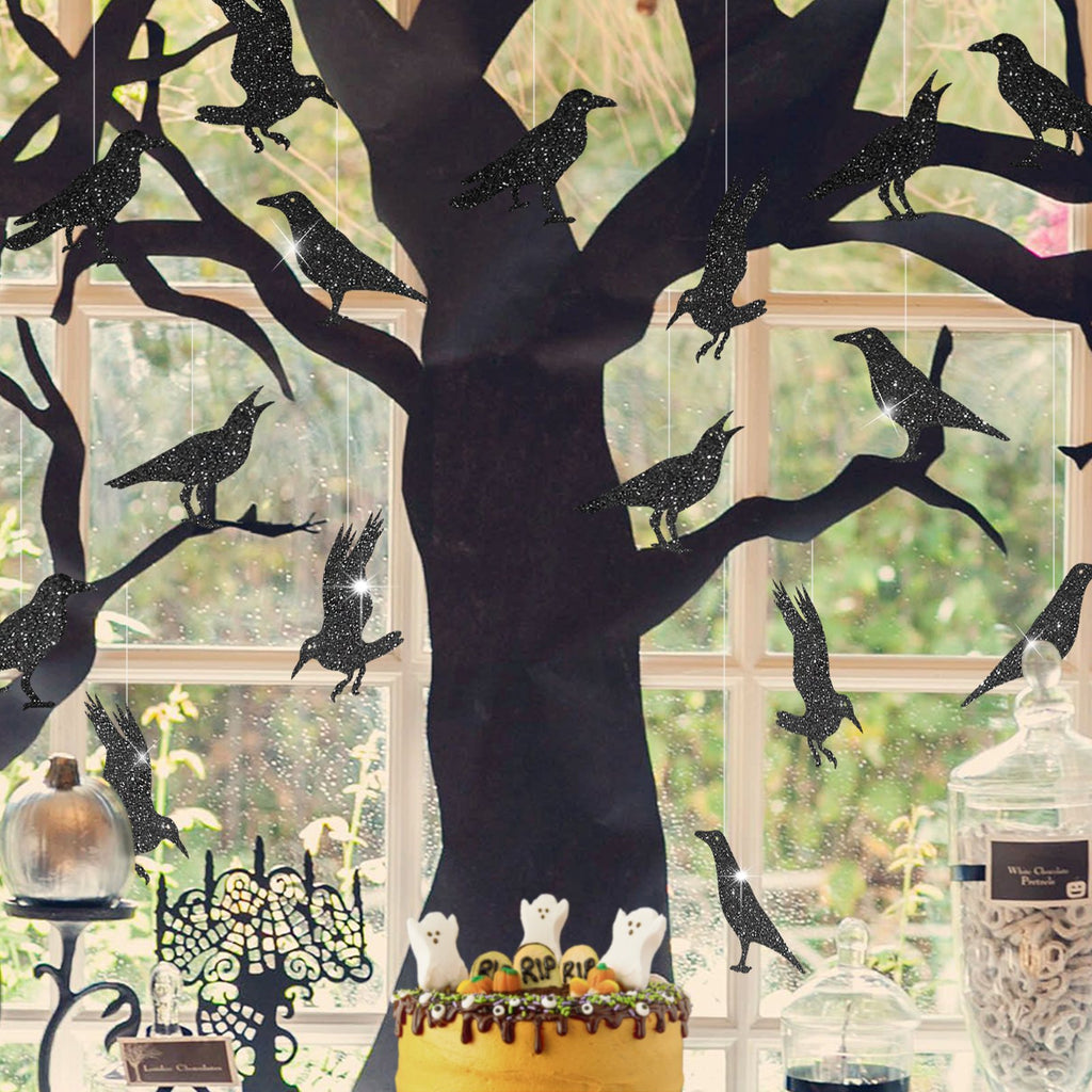 Glitter black crow Halloween decorations hanging from a black tree silhouette against a window