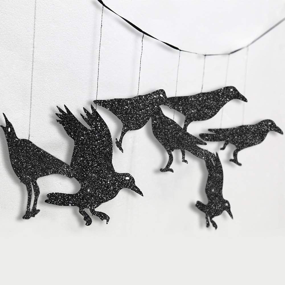 Glitter black crow garland hanging against a white wall, showing multiple crow shapes in various poses.