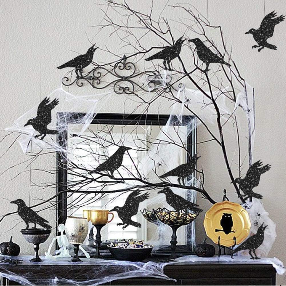 Glitter black crow Halloween decorations arranged on a table with branches and spiderwebs