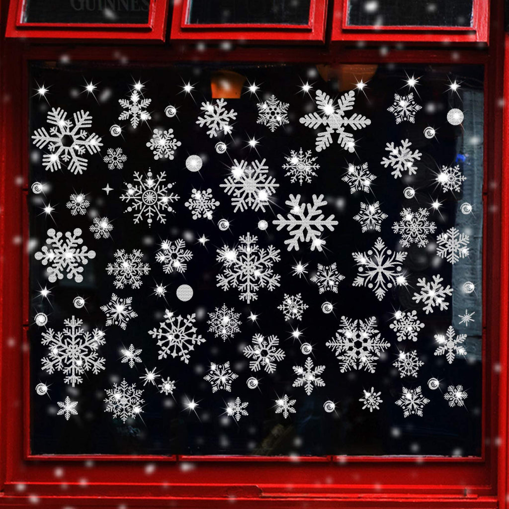 Glitter snowflake window clings applied to a dark window with red trim, showing various sizes and styles of snowflakes and small starbursts.