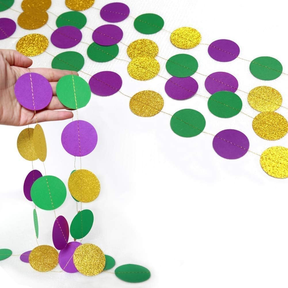 Hand holding a gold, purple, and green glitter circle garland set against a white background.
