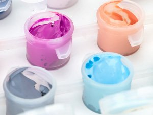 Close-up of open paint pots with purple, orange, blue, and gray acrylic paint.