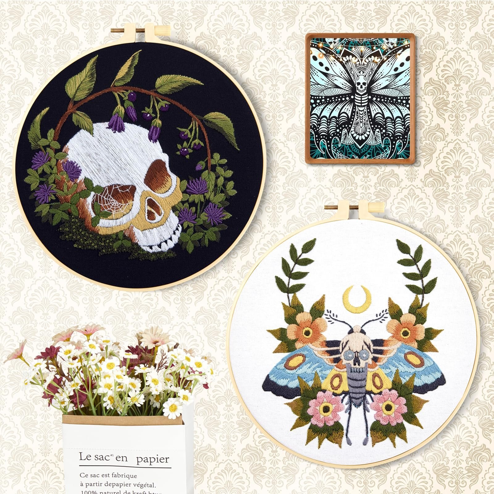 Embroidery hoops with skull and moth designs, framed artwork, and a bouquet of flowers in a paper bag.
