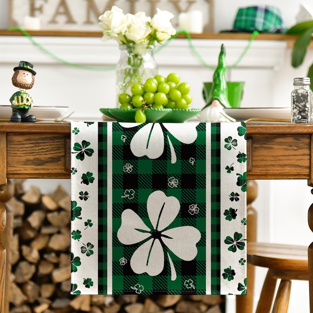 Green clover buffalo plaid table runner with shamrocks, set on a wooden table with decorative items.