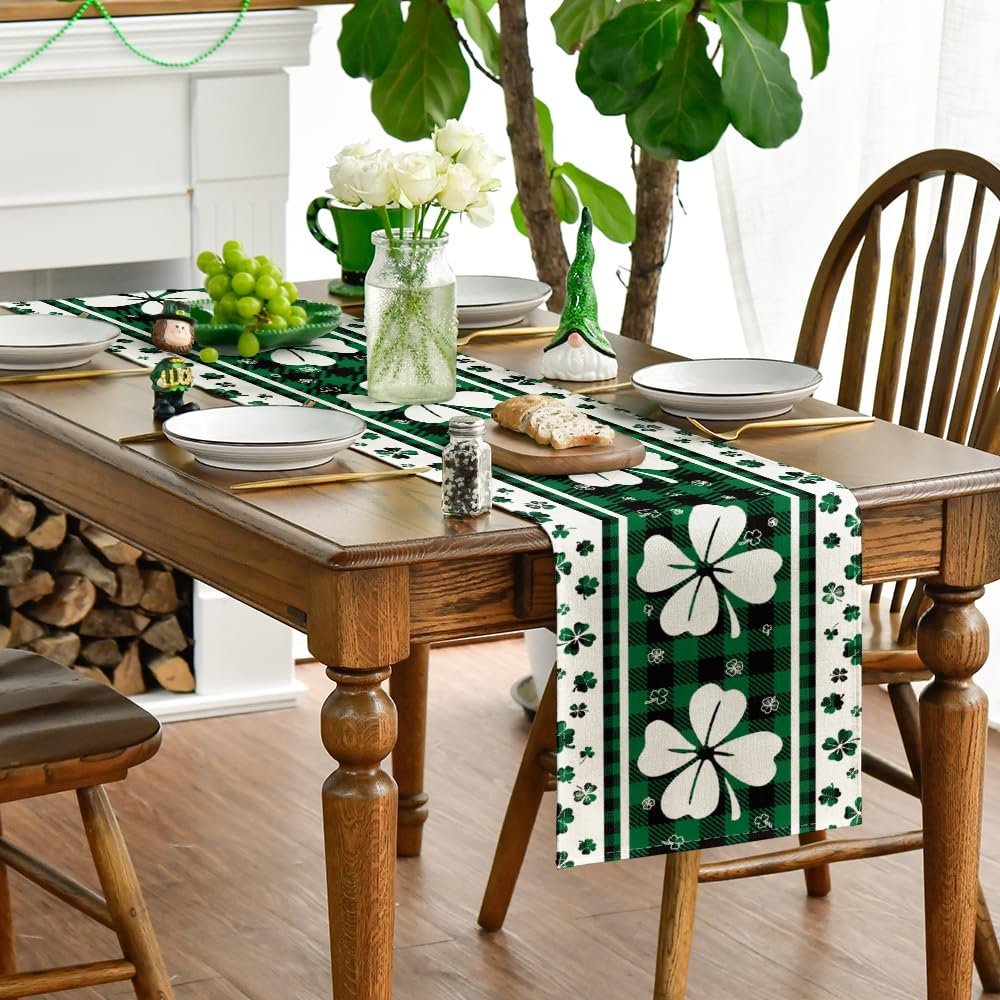 St. Patrick's Day table runner with shamrocks and plaid pattern laid on a wooden dining table with place settings.