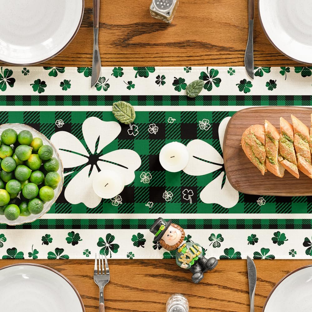 St. Patrick's Day table runner with green buffalo plaid, shamrocks, and white flowers, set on a wooden table with place settings.