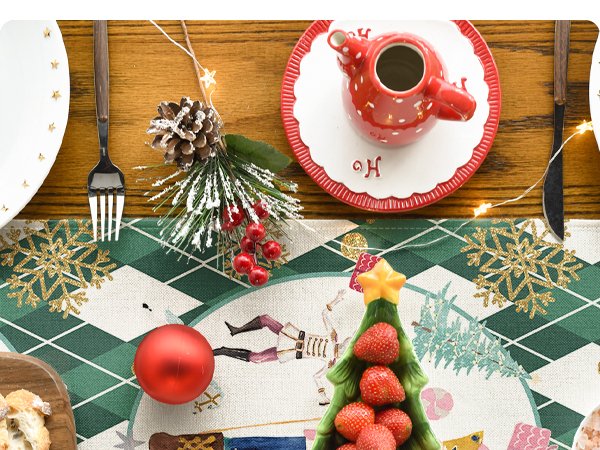 Christmas table runner with green diamond plaid, nutcrackers, snowflakes, and a strawberry-filled tree dish.