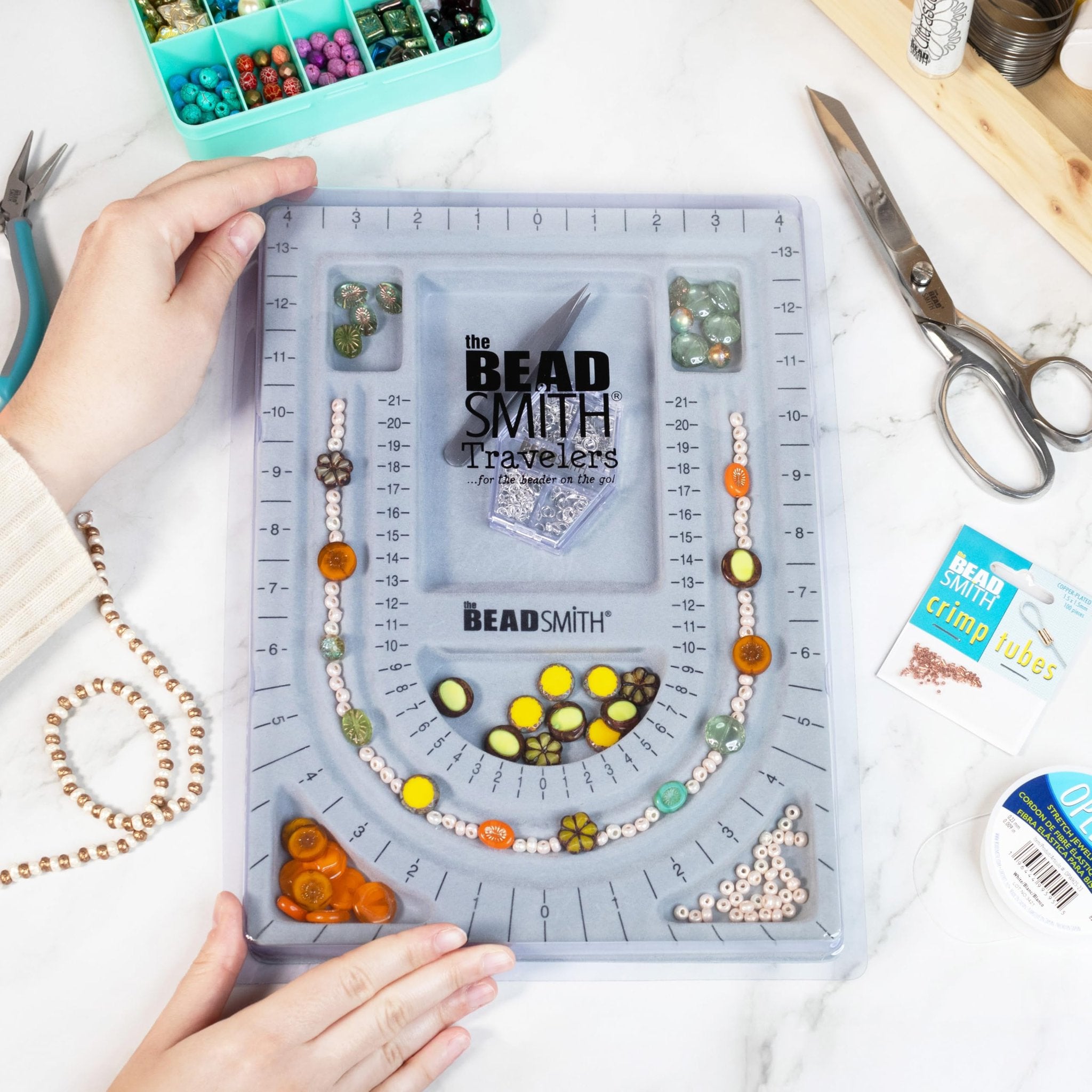 Grey flocked jewelry bead board with beads, tools, and supplies for jewelry making.