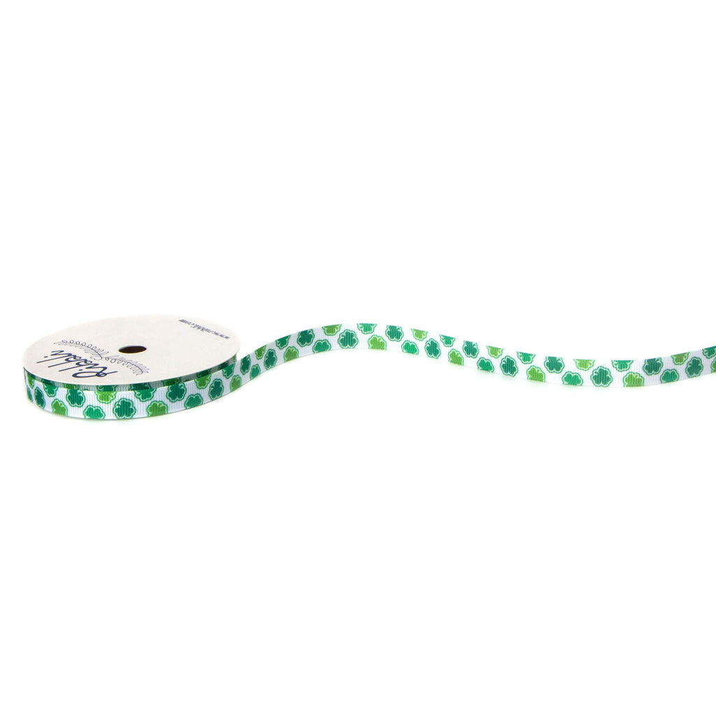 Spool of white grosgrain ribbon with green shamrock pattern and a white ribbon tail on a white background.