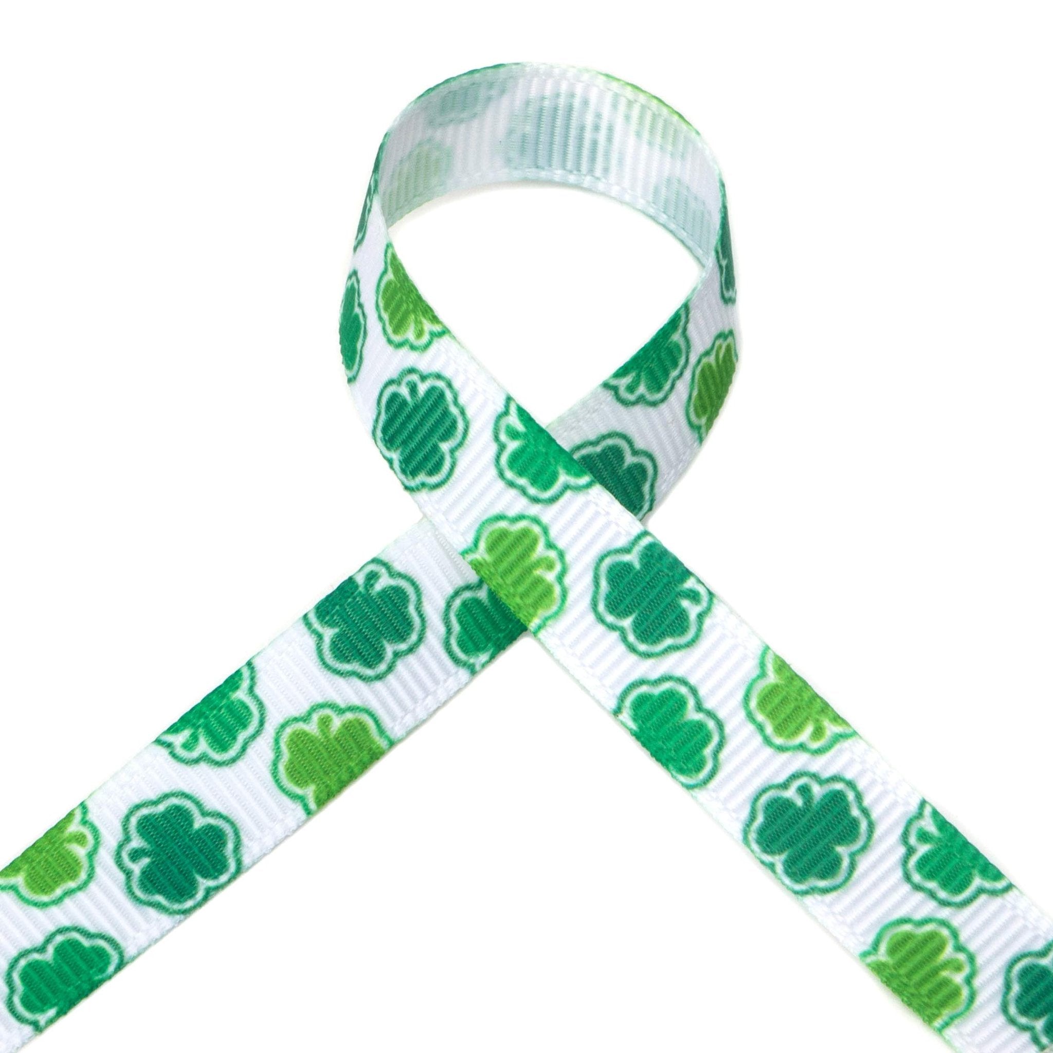 White grosgrain ribbon with green shamrock pattern, tied in a loop against a white background.