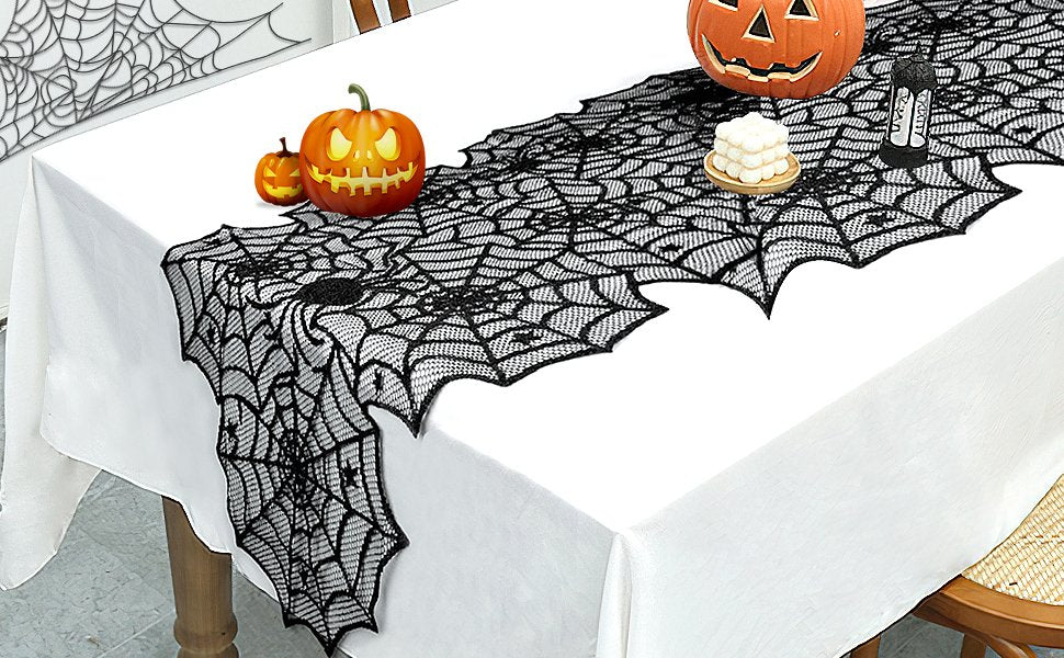 Black lace spider web table runner draped on a white tablecloth with Halloween decorations