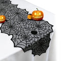 Black lace spider web table runner with decorative Halloween pumpkins on a white tablecloth