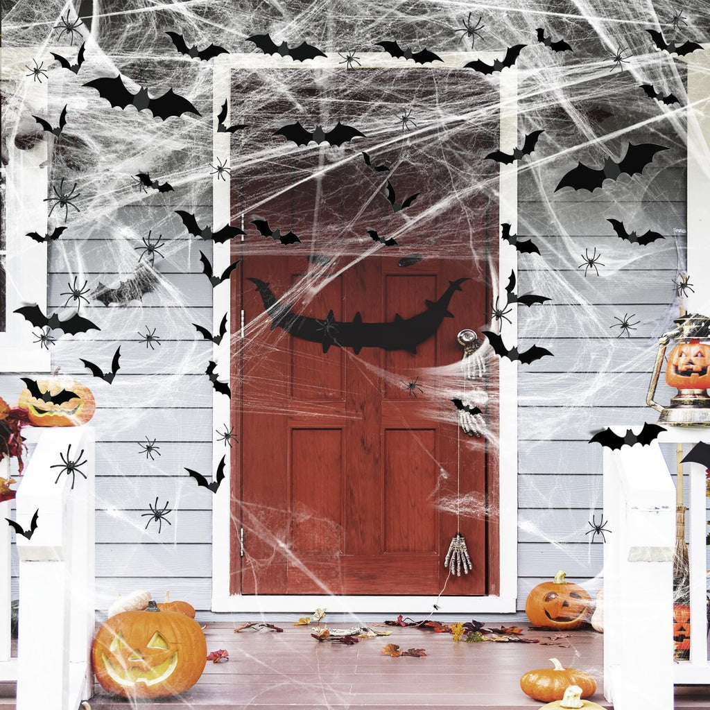 Halloween porch decorated with fake spider webs, bats, spiders, and pumpkins.