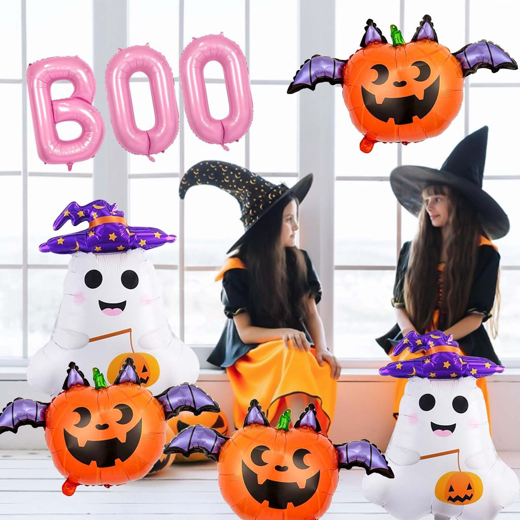 Halloween foil balloons including pink BOO letters, ghost, and pumpkin shapes with bat wings, with two children in witch costumes in the background.