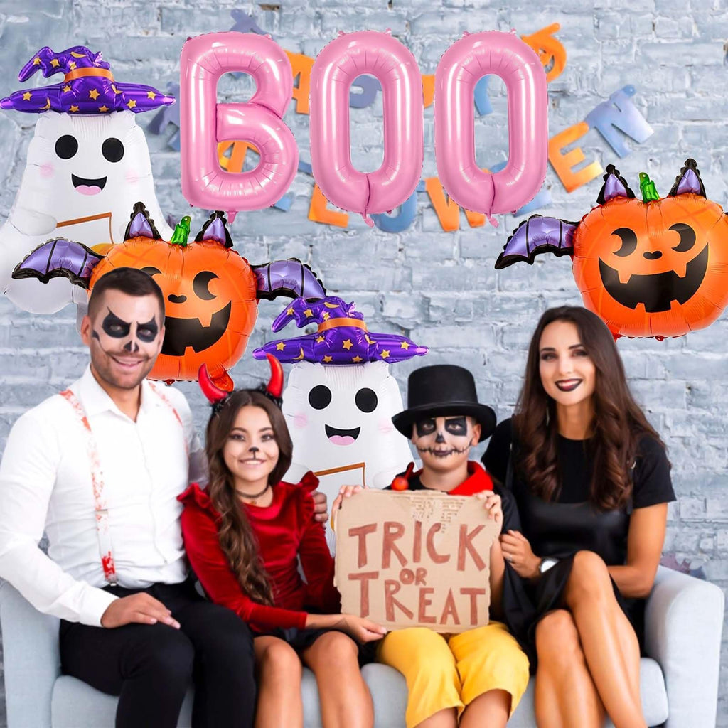 Family in Halloween costumes posing with pink BOO balloons, ghost and pumpkin balloons