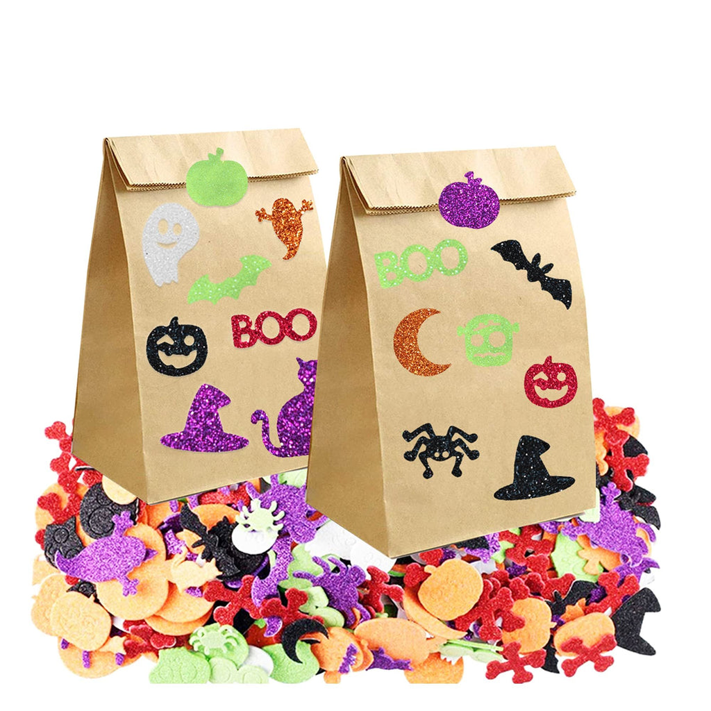 Two brown paper bags decorated with Halloween glitter foam stickers, surrounded by a pile of assorted foam stickers.