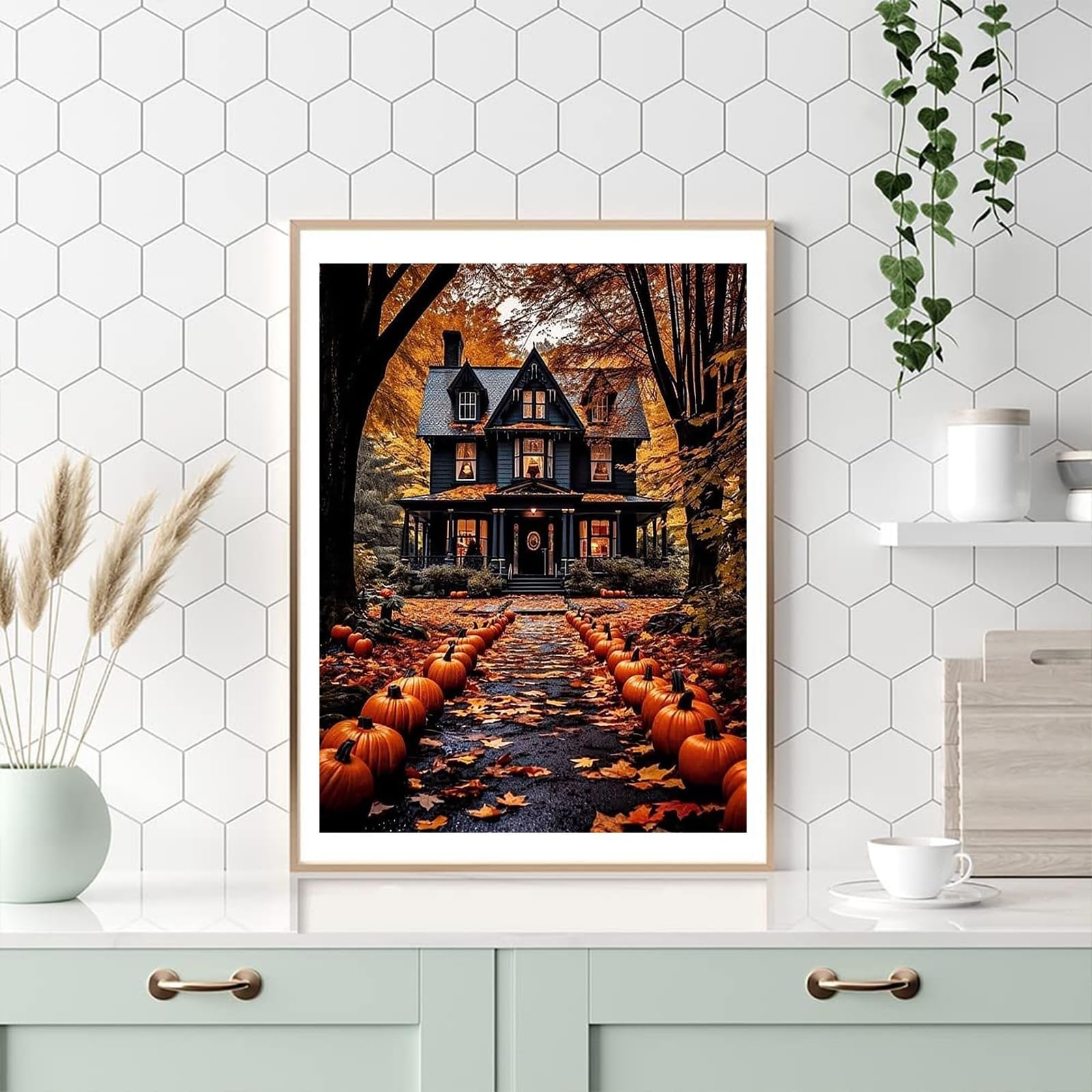 Framed painting of a dark, haunted-style house with a path lined by pumpkins and fallen leaves, set against an autumn forest backdrop.