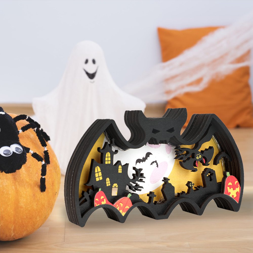 Halloween light-up bat shadow box with haunted house, pumpkins, and ghost on a wooden surface.