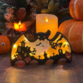 Light-up Halloween bat shadow box with haunted house, ghost, bats, and pumpkins, set against a festive backdrop.