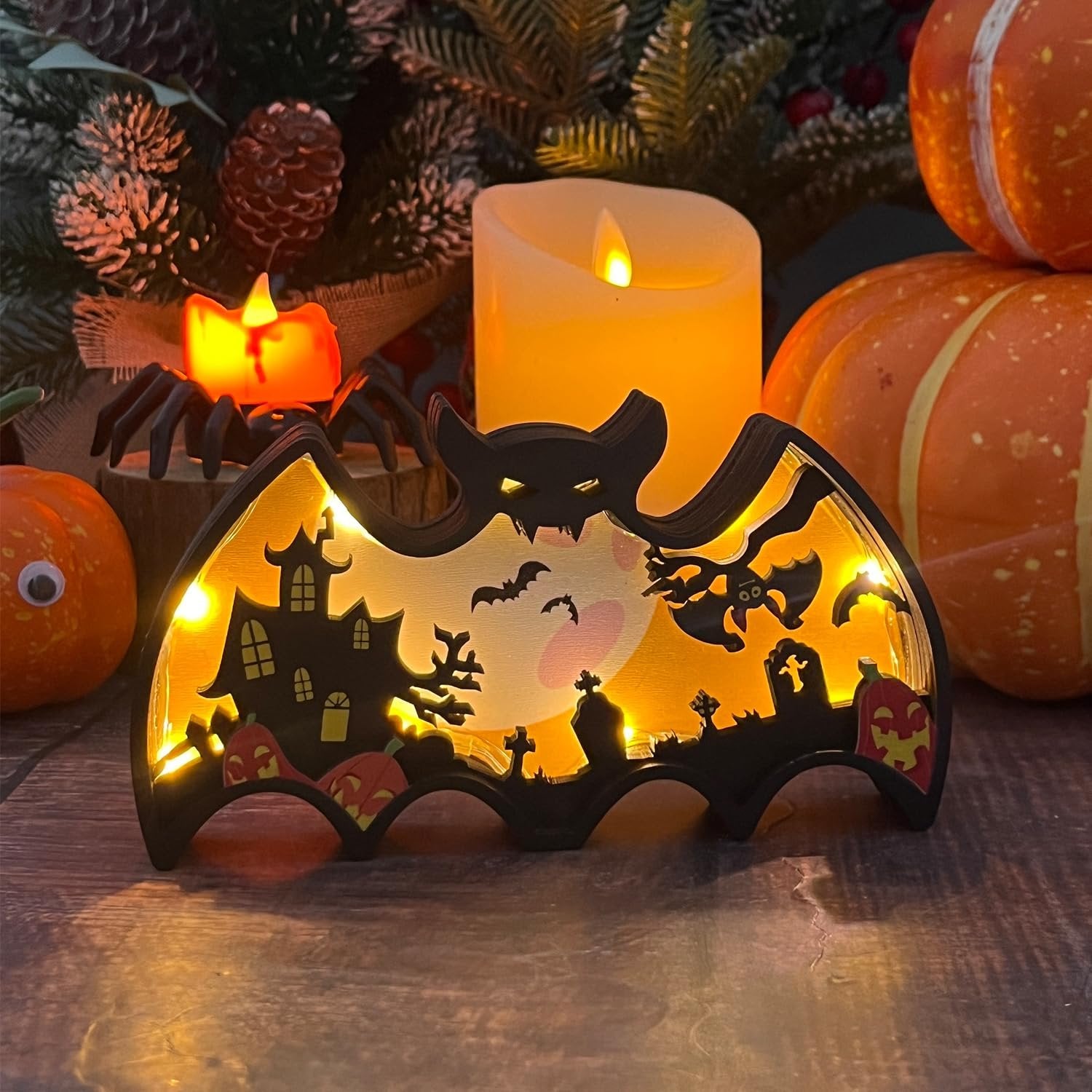 Light-up Halloween bat shadow box with haunted house, ghost, bats, and pumpkins, set against a festive backdrop.