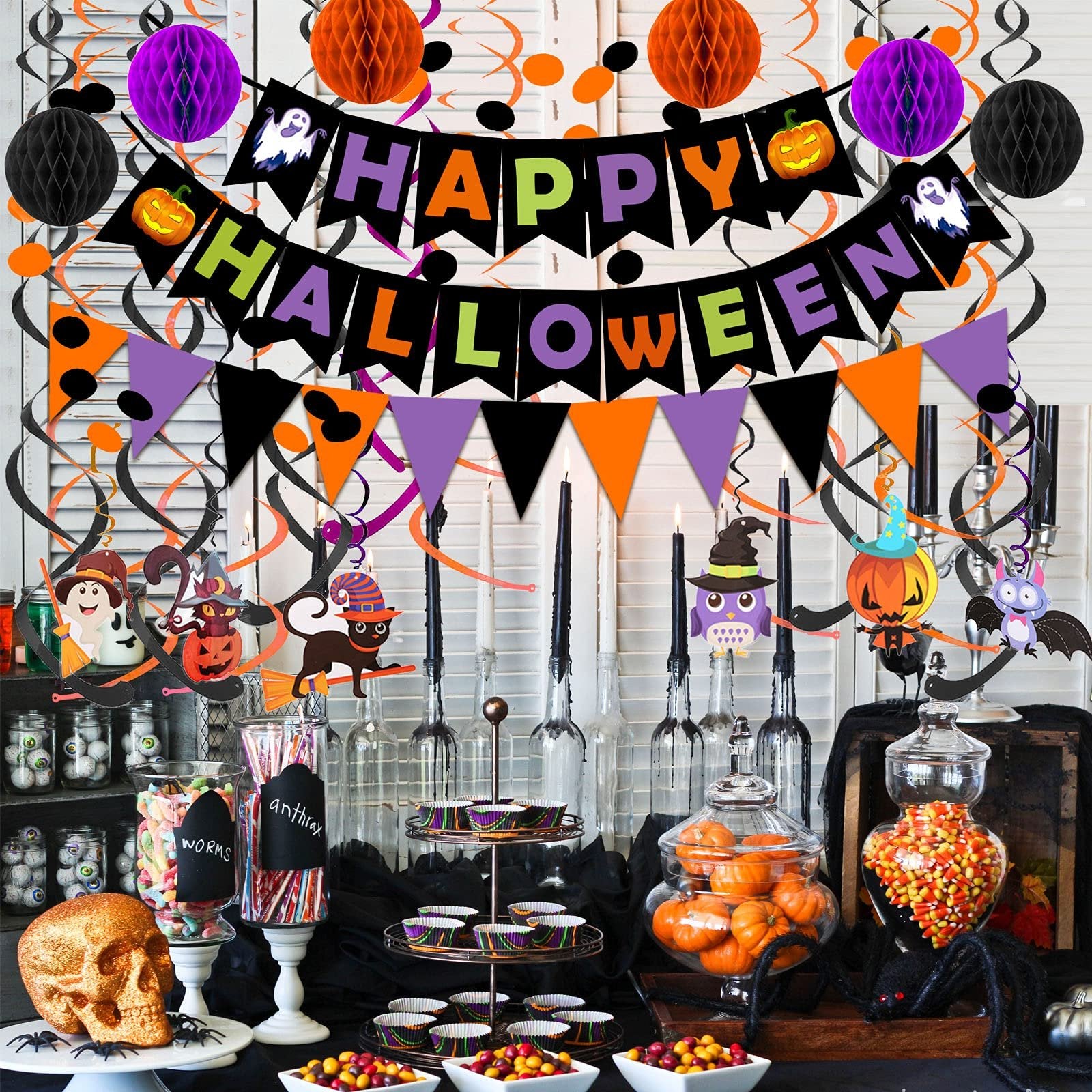 Halloween party table setting with decorations, candy, and pumpkins.