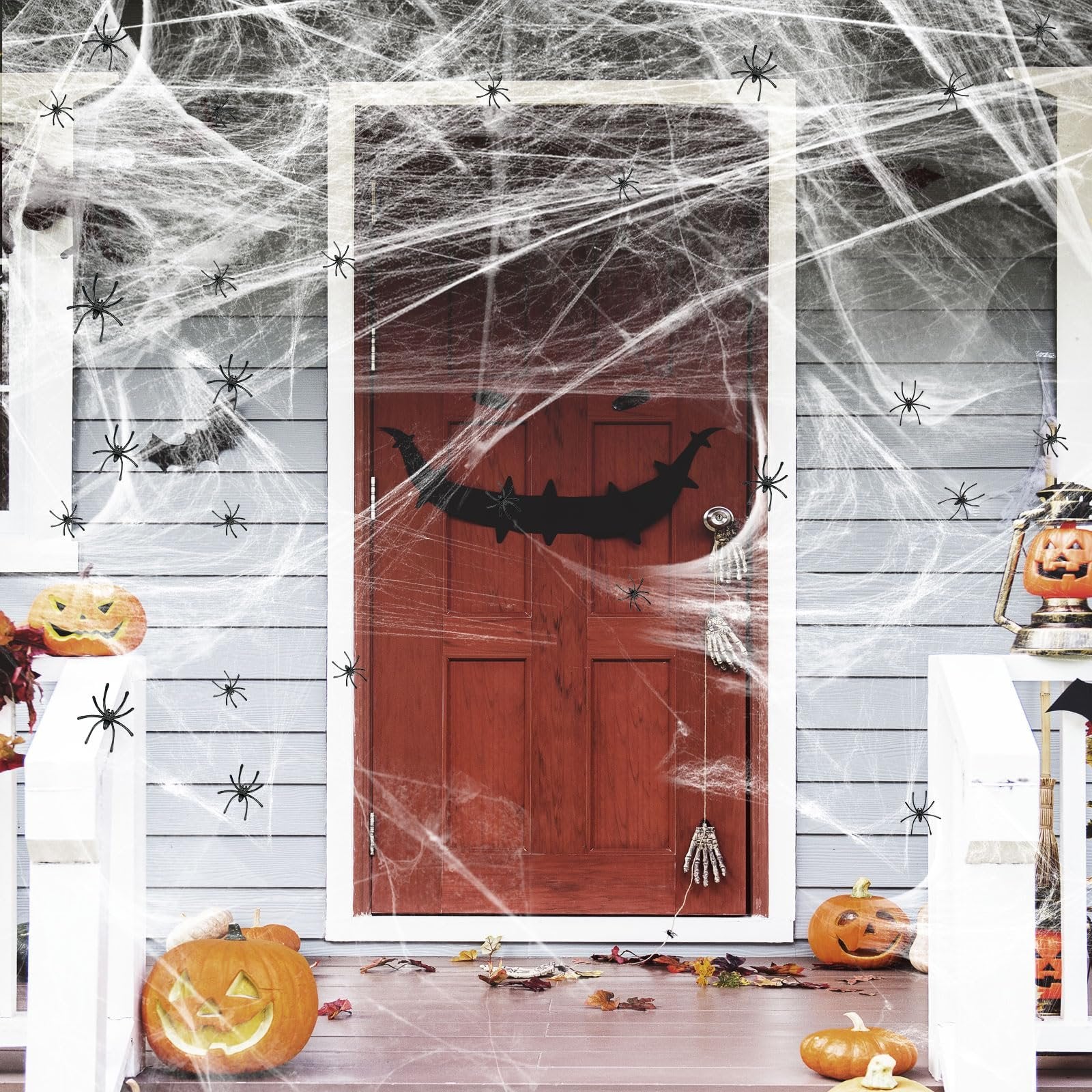 Halloween decorated front porch with red door, pumpkins, cobwebs, and spiders