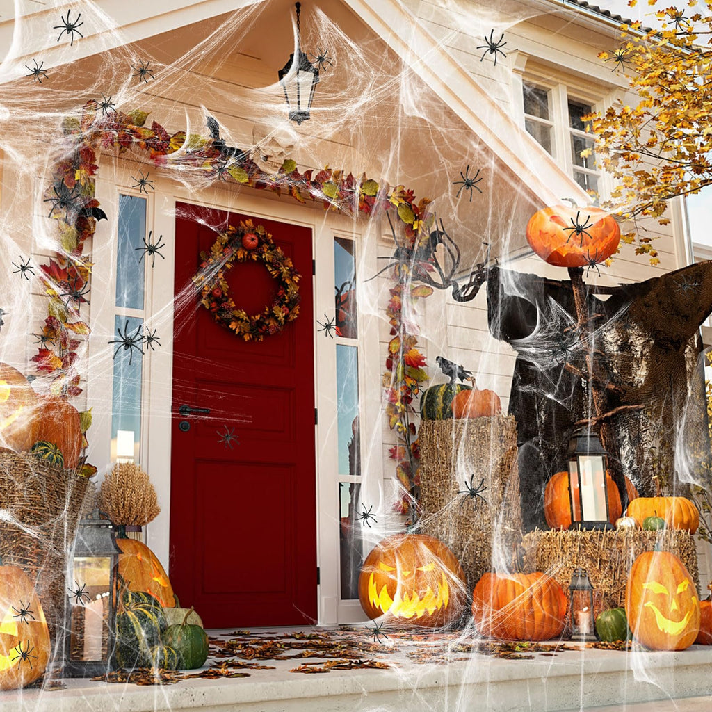 Halloween porch decorated with stretchable cobwebs, fake spiders, pumpkins, and a wreath on the door.
