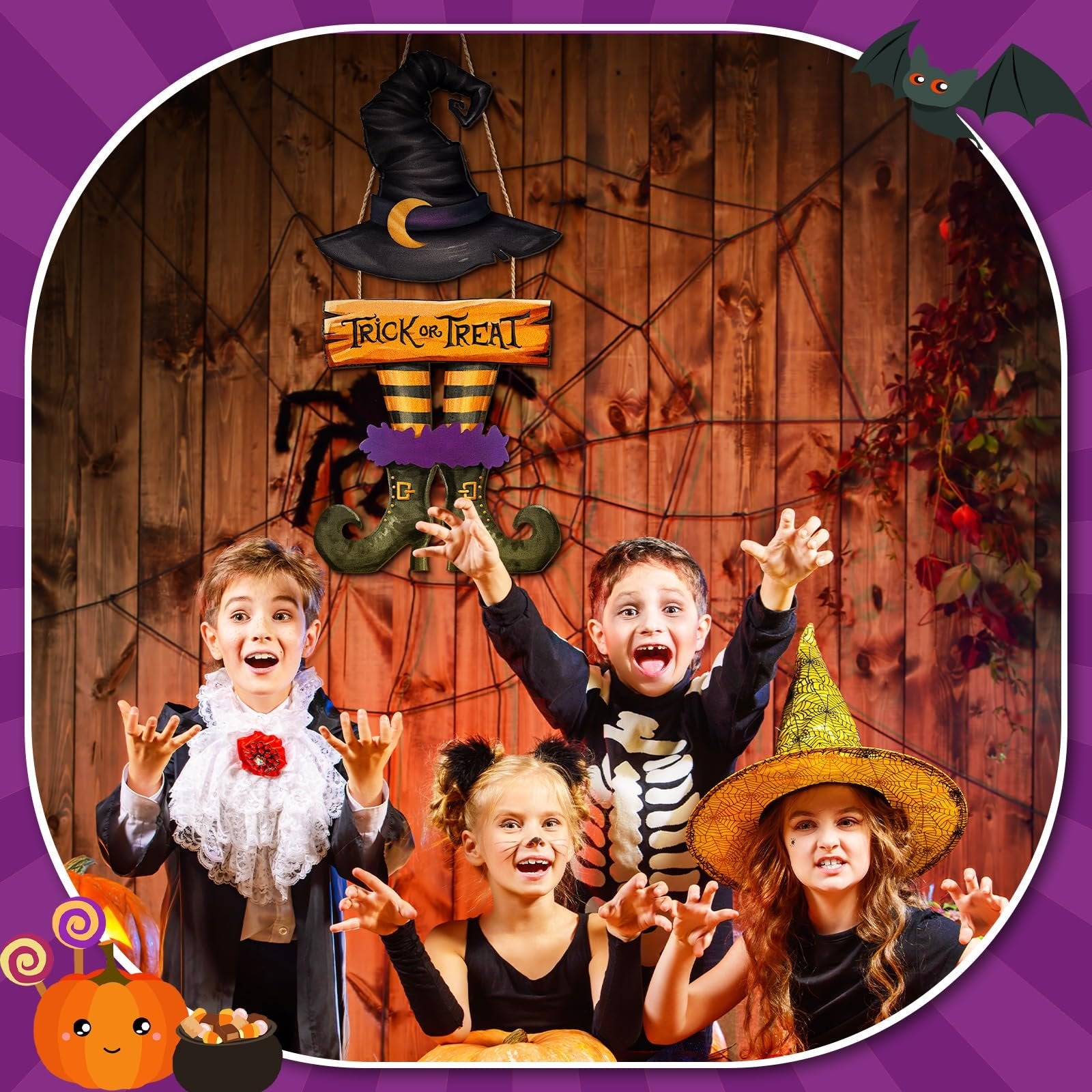 Four children in Halloween costumes pose in front of a wooden wall with a trick or treat sign and spiderwebs