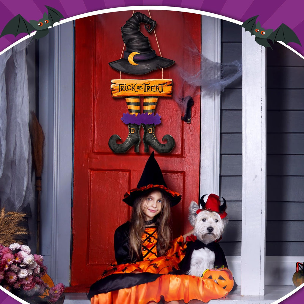 Halloween witch hat and legs door sign hanging on a red door with a girl and dog in costumes on the porch