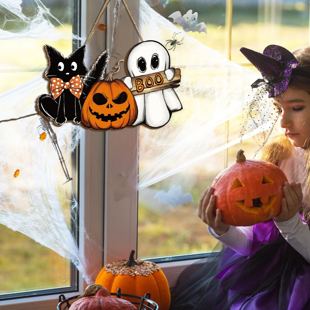 Halloween hanging door sign with black cat, pumpkin, and ghost, displayed on a window with fake spiderwebs.