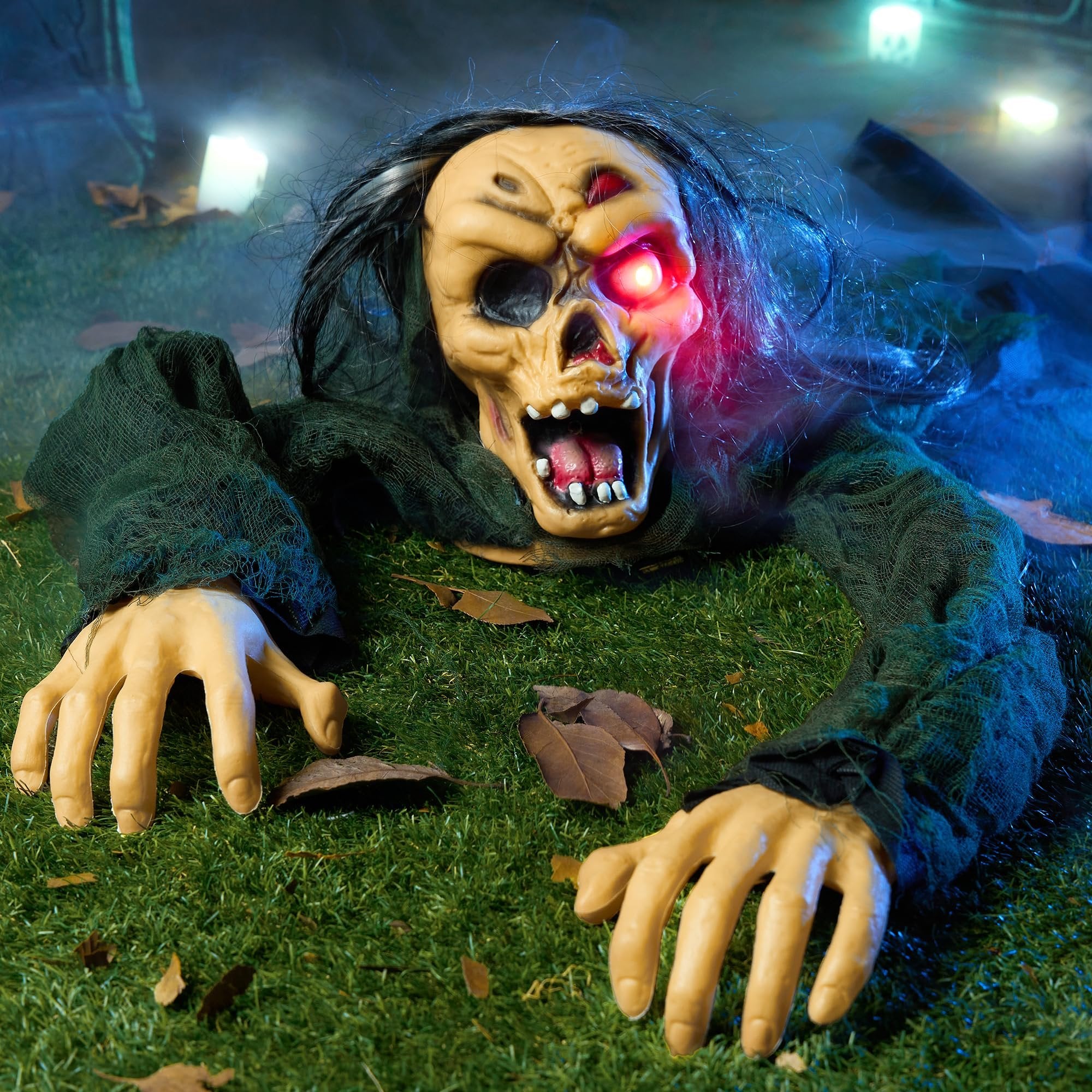 Scary zombie prop emerging from the ground with glowing red eyes and tattered clothes, Halloween decoration.