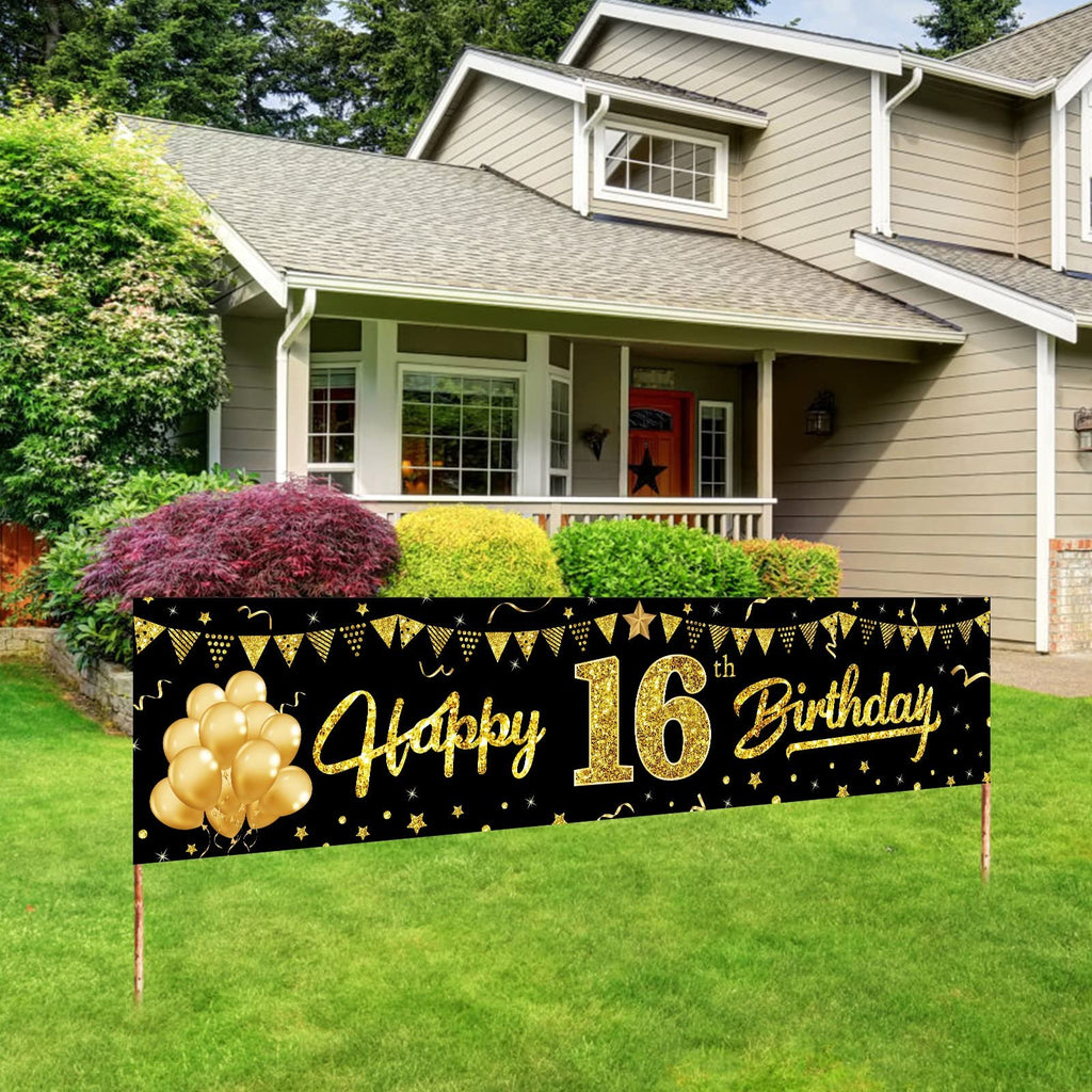 Black and gold 'Happy 16th Birthday' banner with balloons and confetti displayed on a lawn in front of a house.