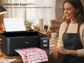 Woman smiling while looking at a printer printing sheets of heart-patterned paper.