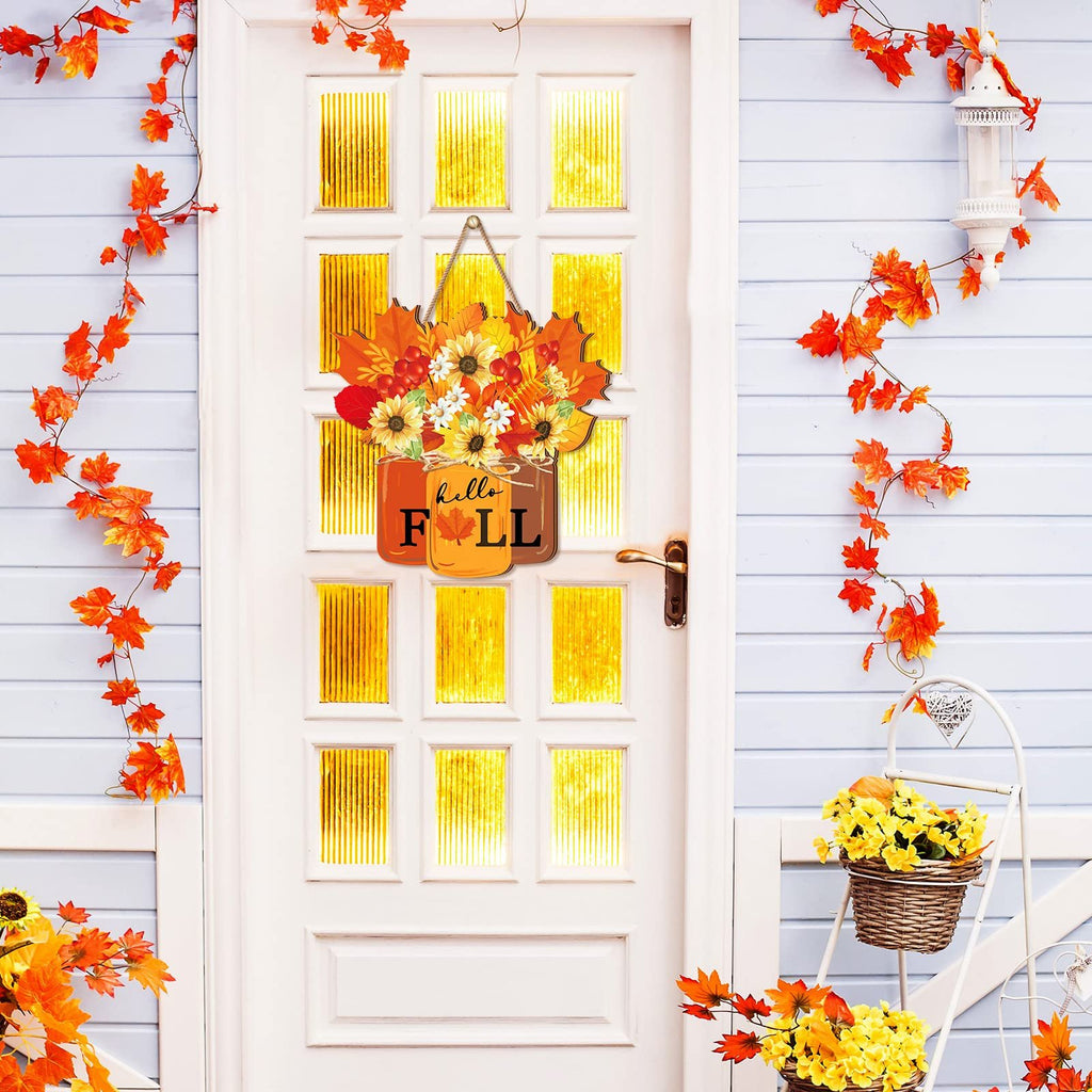 Autumn door sign with sunflowers and maple leaves hanging on a white door with fall foliage decorations.