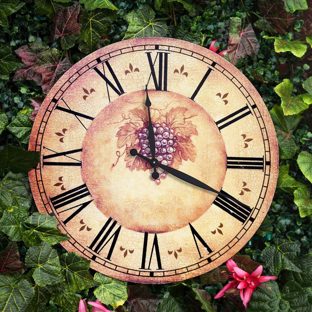 Vintage-style clock face with Roman numerals and grape cluster design, set against a backdrop of green ivy and pink flowers.