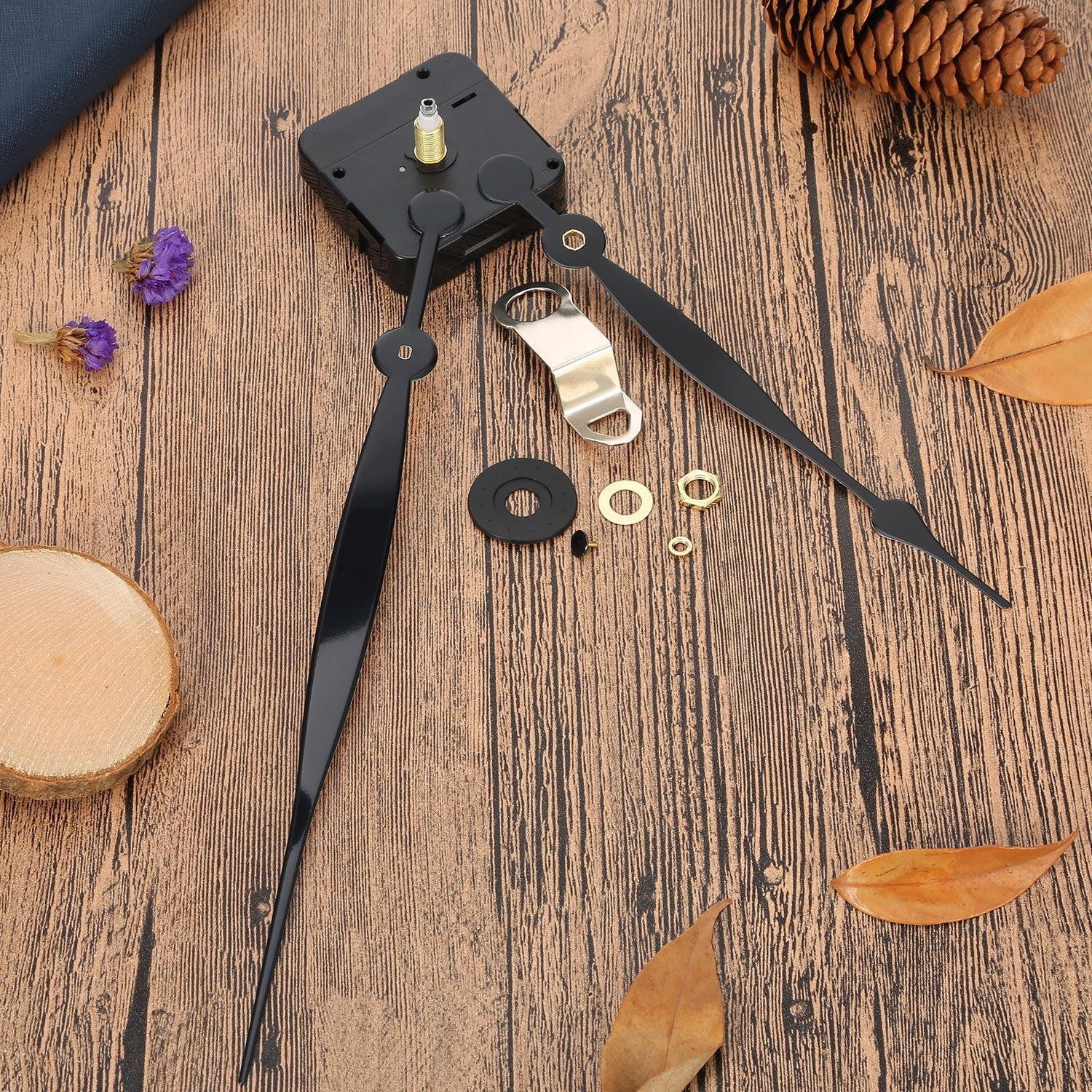 Clock movement replacement kit with black hands and hardware laid out on a wooden surface with decorative elements.