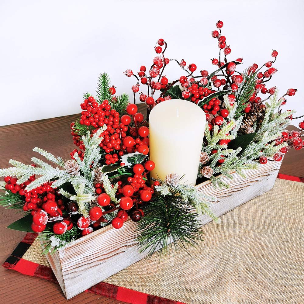 Christmas berry centerpiece with a candle in a wooden planter, decorated with pine sprigs and red berries.
