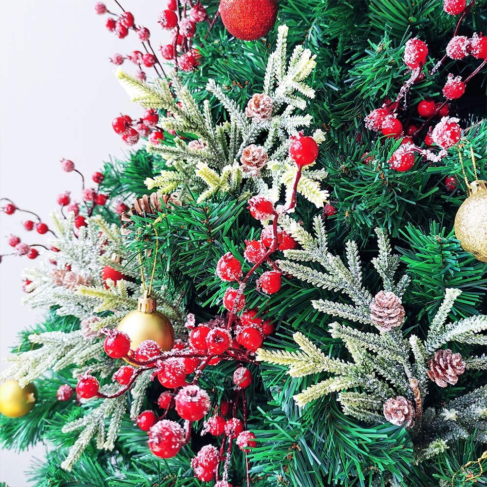 Close-up of artificial Christmas berry sprays with red berries and pinecones on a green tree.