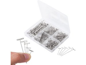 Hand holding several T-pins with a clear plastic organizer box filled with T-pins in the background.