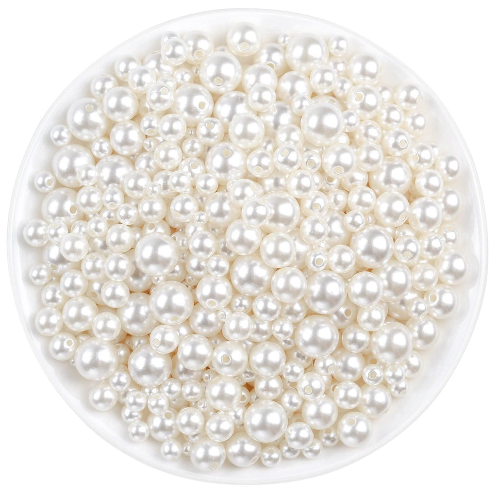 Ivory pearl craft beads in assorted sizes poured into a white bowl, top-down view.